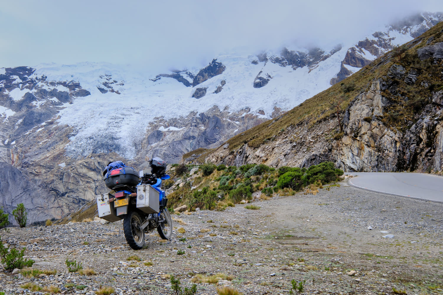 motorcycle parked with glaciers spilling down behind