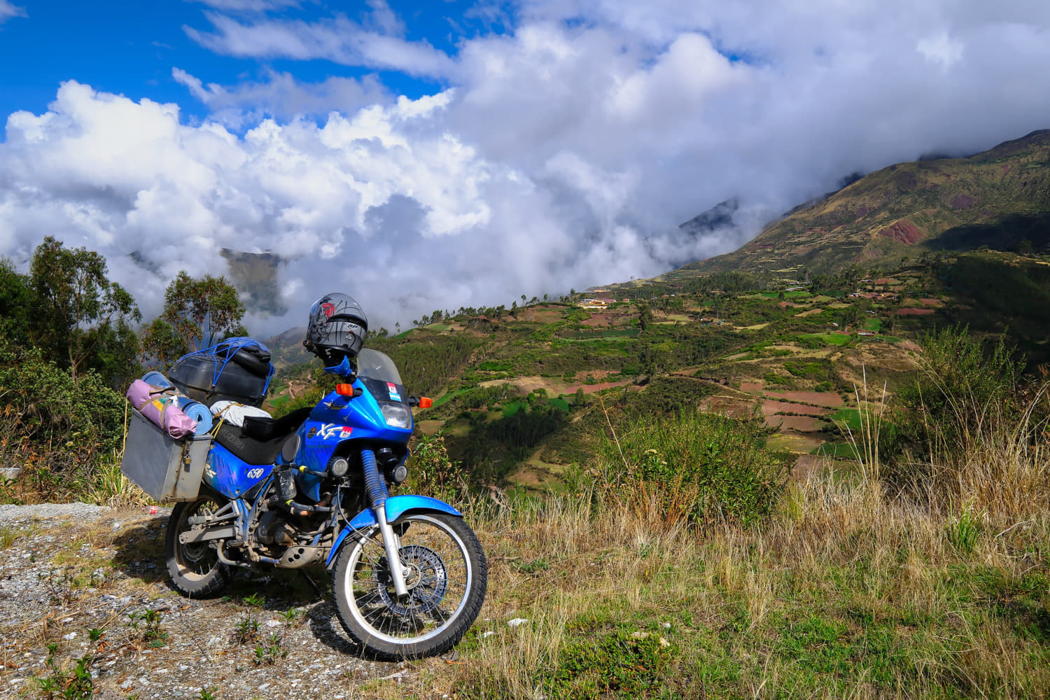 motorcycle parked on a mountains with clouds behind