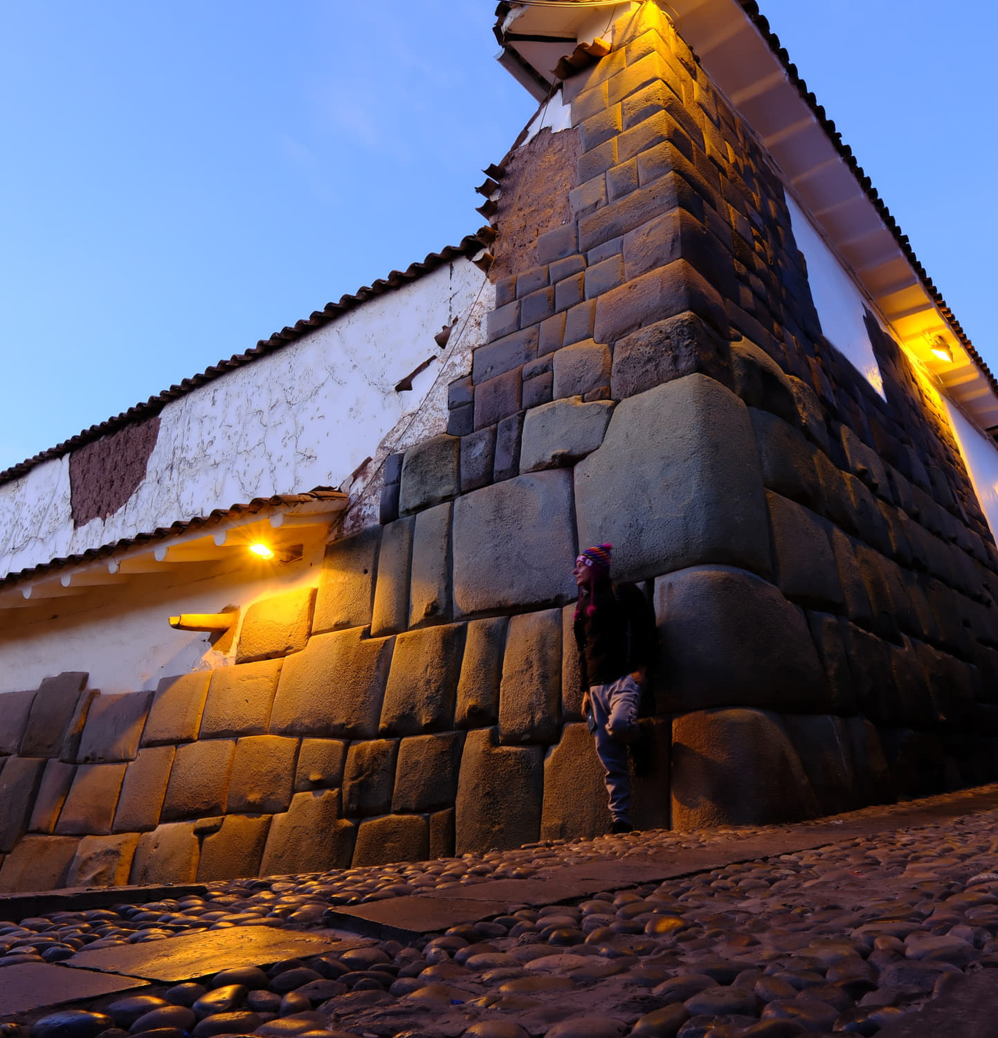 posing at a corner next to stacked Inca rocks