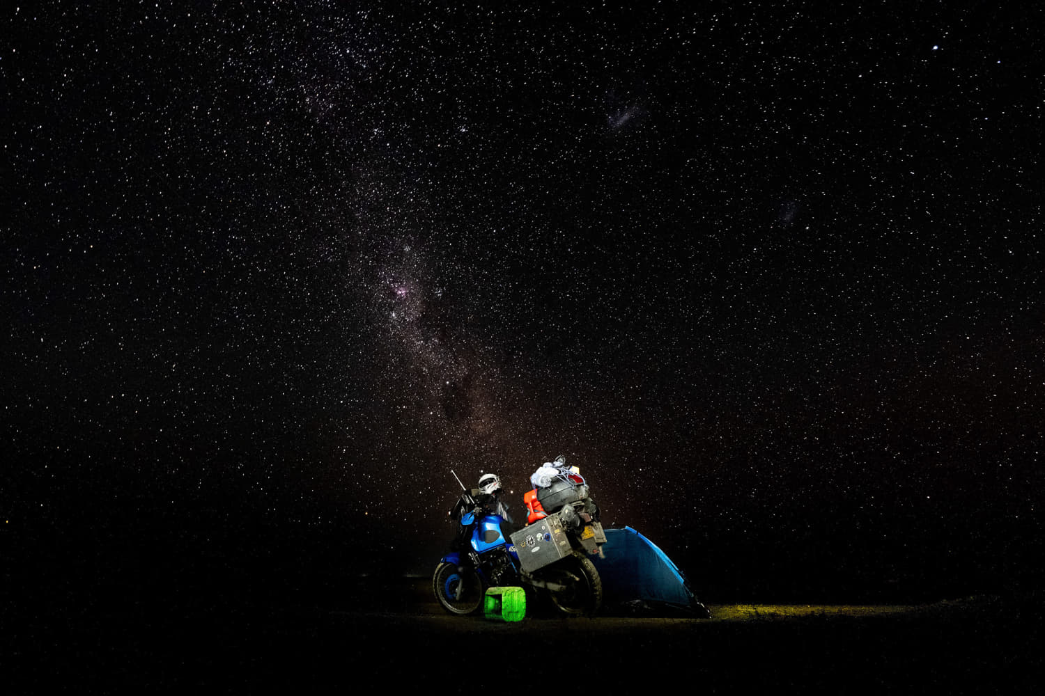  motorcycle parked next to a tent and countless starts above