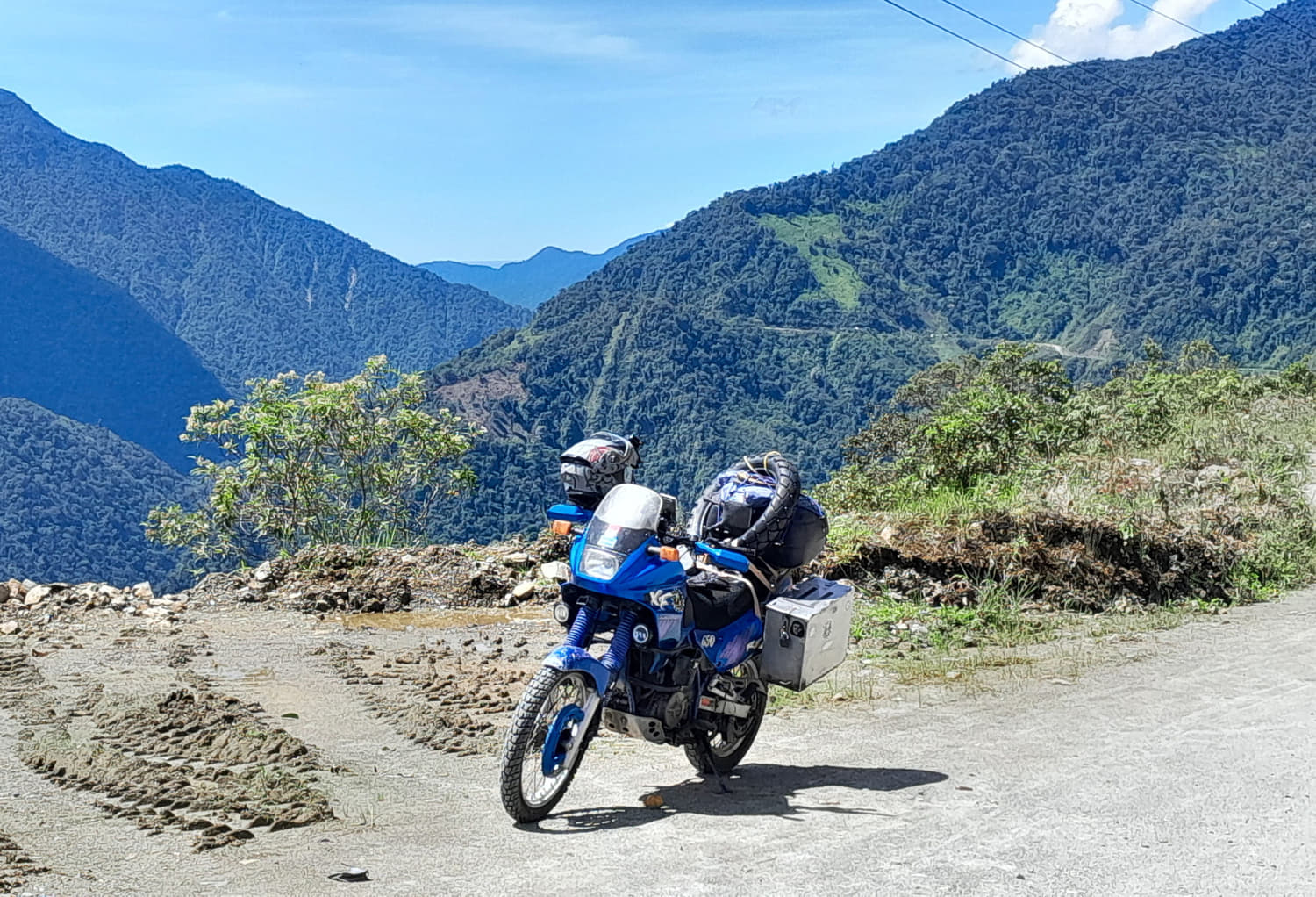 motorcycle parked on a road with jungle covered mountains behind 