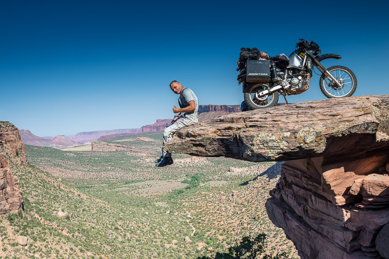 Sitting on an overhanging rock with motorcycle parked