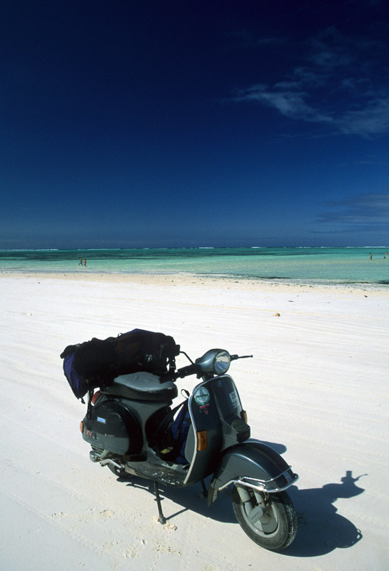 a scooter parked on white sand bach