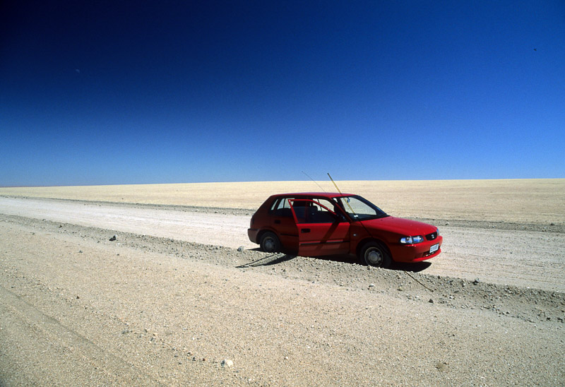 red car parked in a tree-less desert