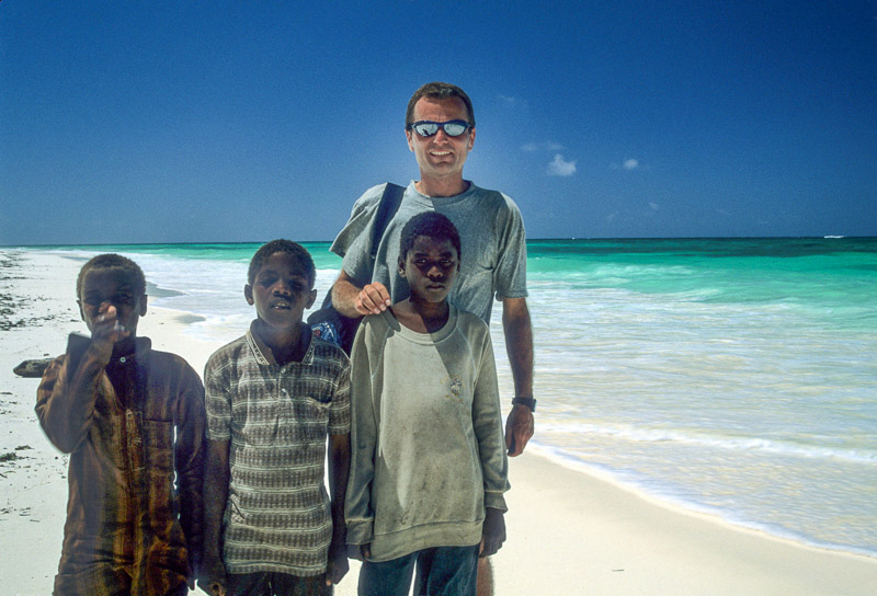 posing with local kids on a dazzling white sand beach