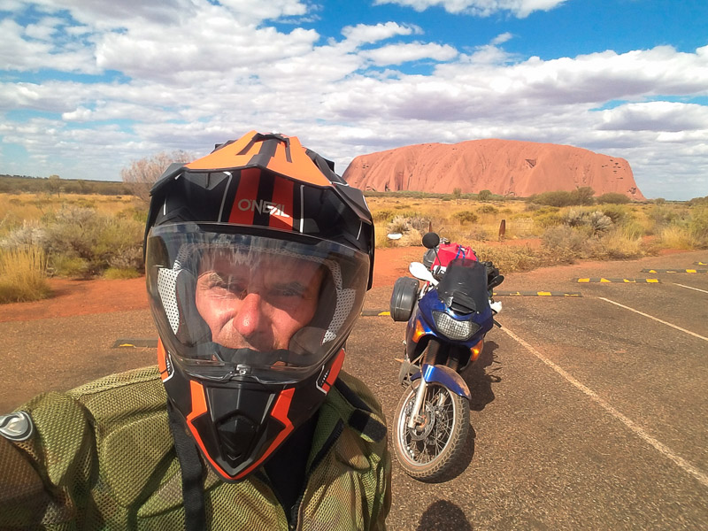 a motorcycle with a helmet on and Ayers Rock behind