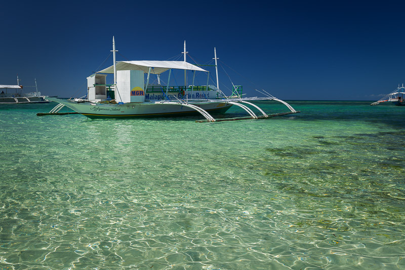 white catamarans anchored in shallow crystal-clear waters