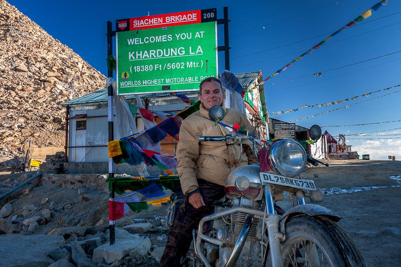 person posing next to a sign Khardung La Pass