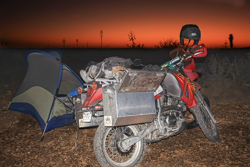 Motorcycle and tent with red sky behind