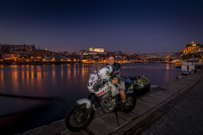 Sitting on a motorcycle with glittering lights of Porto behind