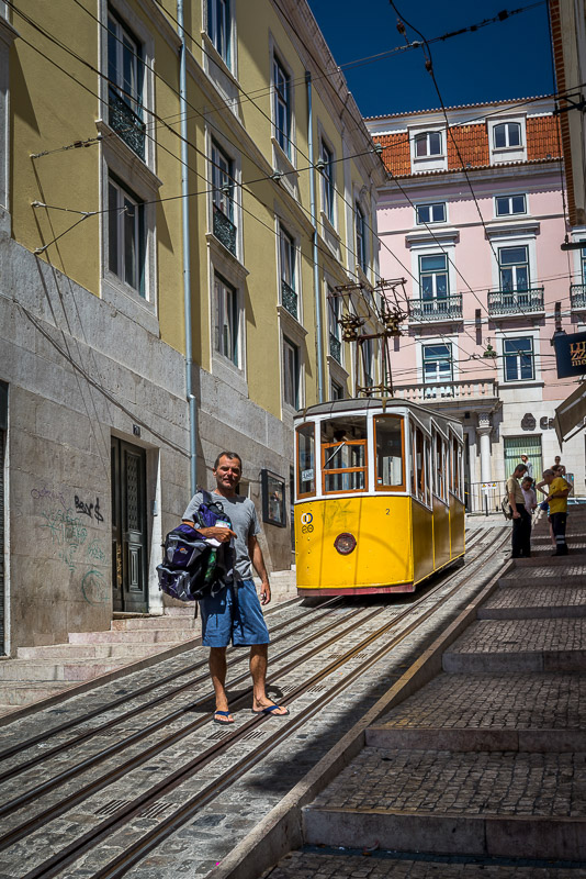 posing in front of a yellow cable car on a steep lisbon street