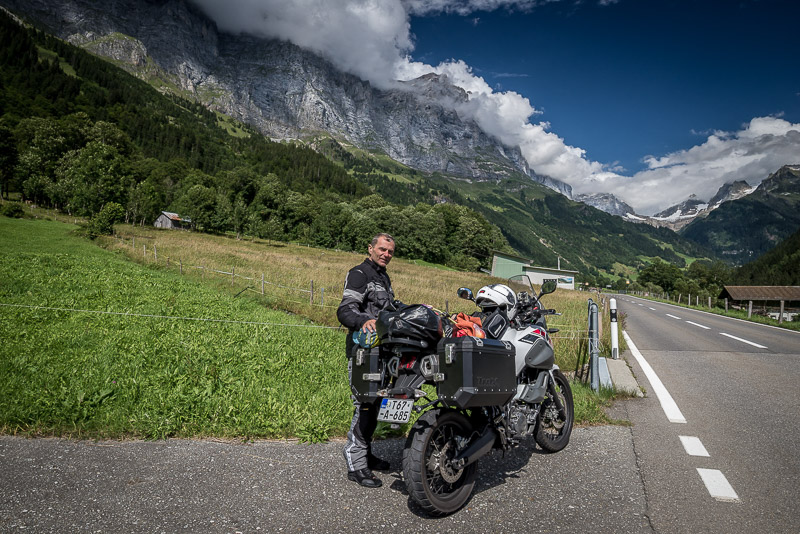 Motorcycle in a green valley surrounded by steep mountains