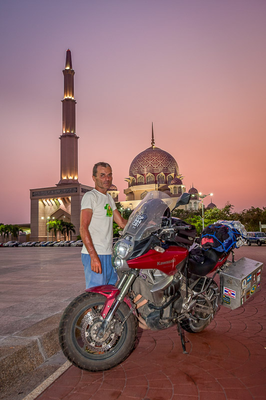 motorcycle and rider in front of a mosque after sunset