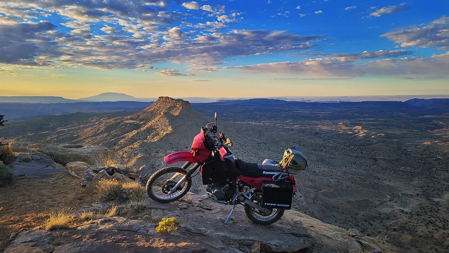 Motorcycle parked at the edge of a mesa with desert valley behind