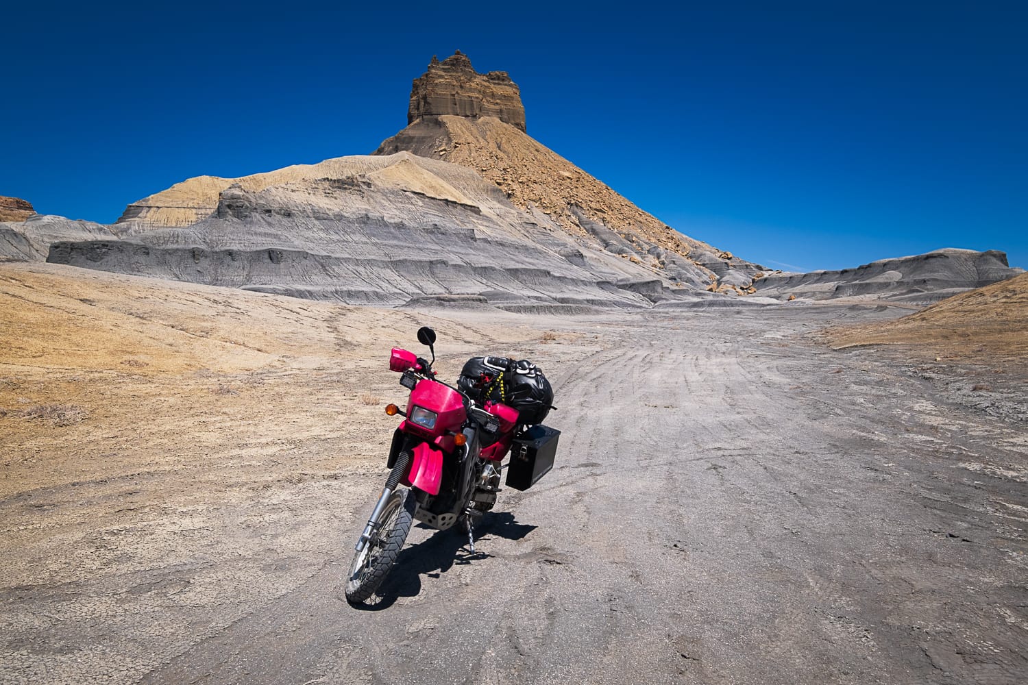 Motorcycle on a dirt road with towering mesa behind