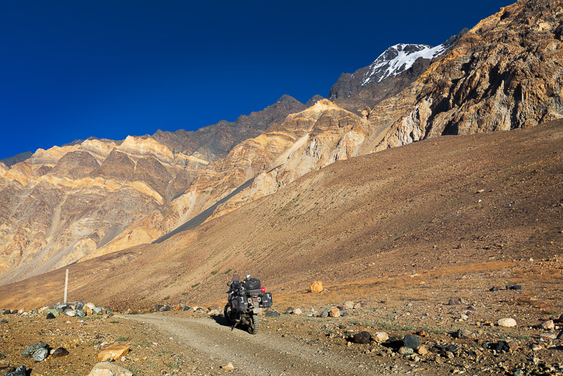 motorcycle on a dirt road with bright-yellow colored mountains behind