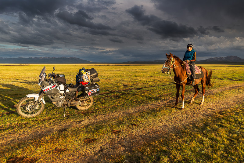 Kyrgyz kid on a horse next to a motorcycle