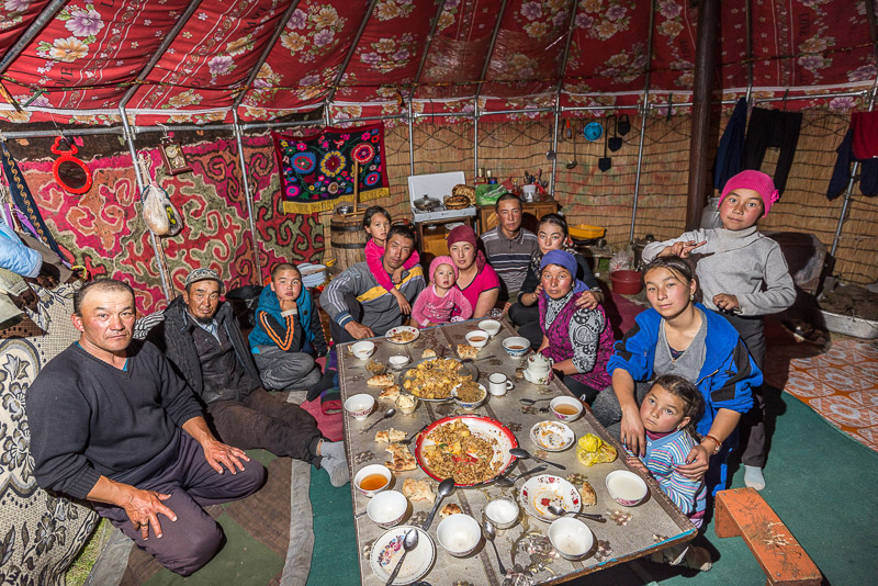 Kyrgyz family at a dinning table inside a yurt