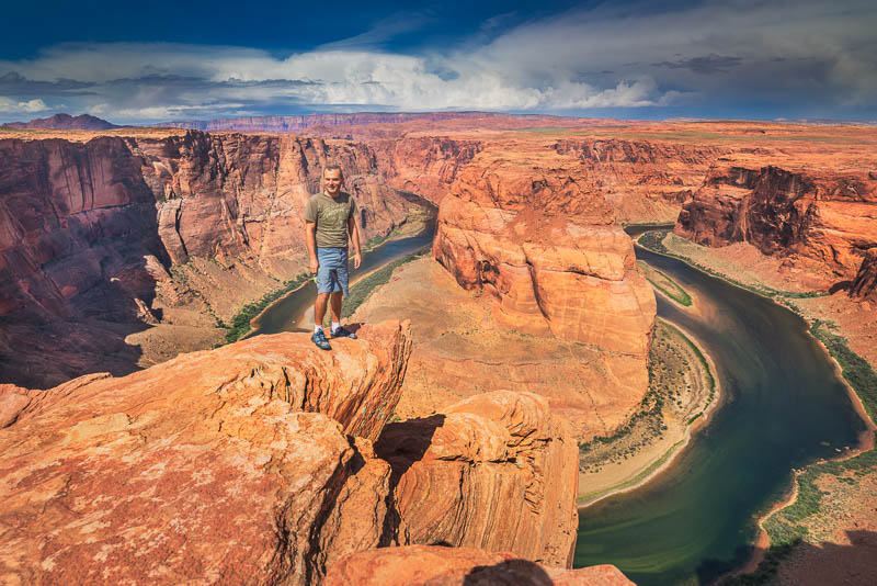 standing at the edge of a cliff high above a 180 degree curve in a canyon