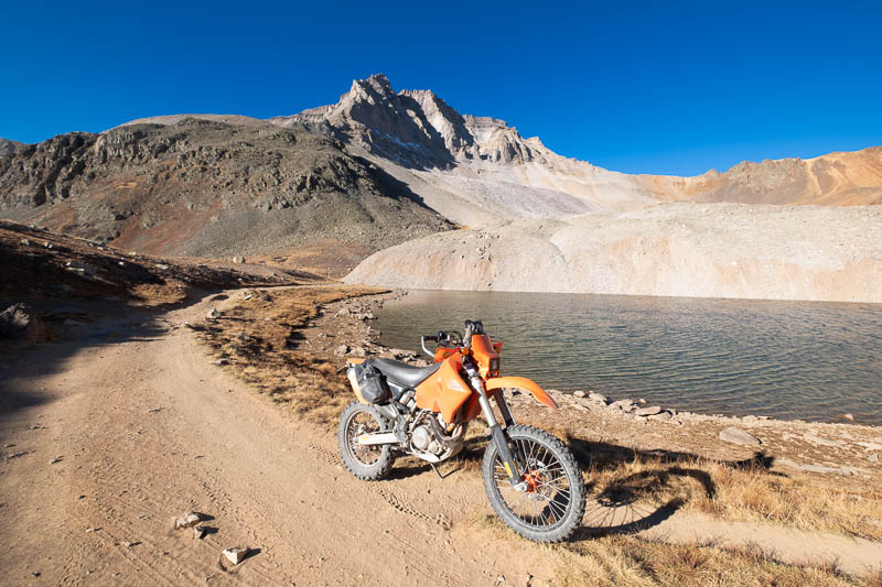 motorcycle parked in front of a high alpine lake