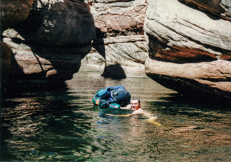 swimming in a canyon with backpack on an inflatable raft