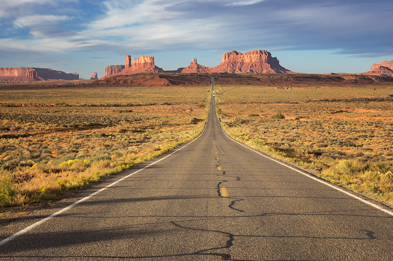 a straight section of the road going towards spires of Monument Valley in the distance