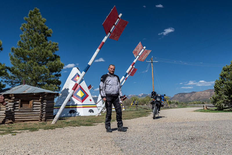 motorcycle and rider next to a big teepee and huge arrows