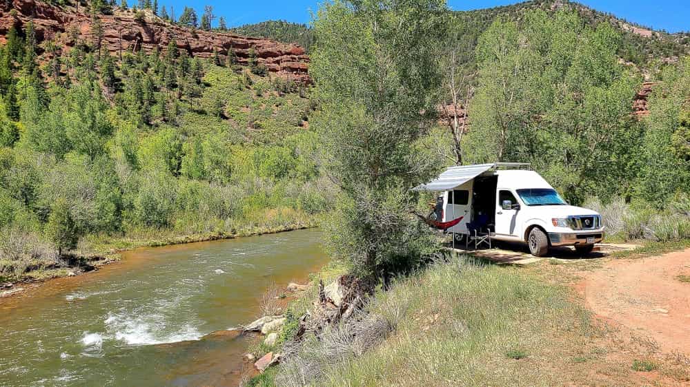 van with awning extended parked next to a river