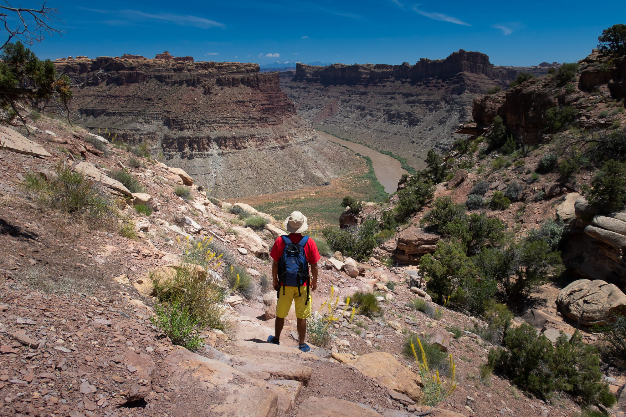 a person hiking down a steep slope towards river 