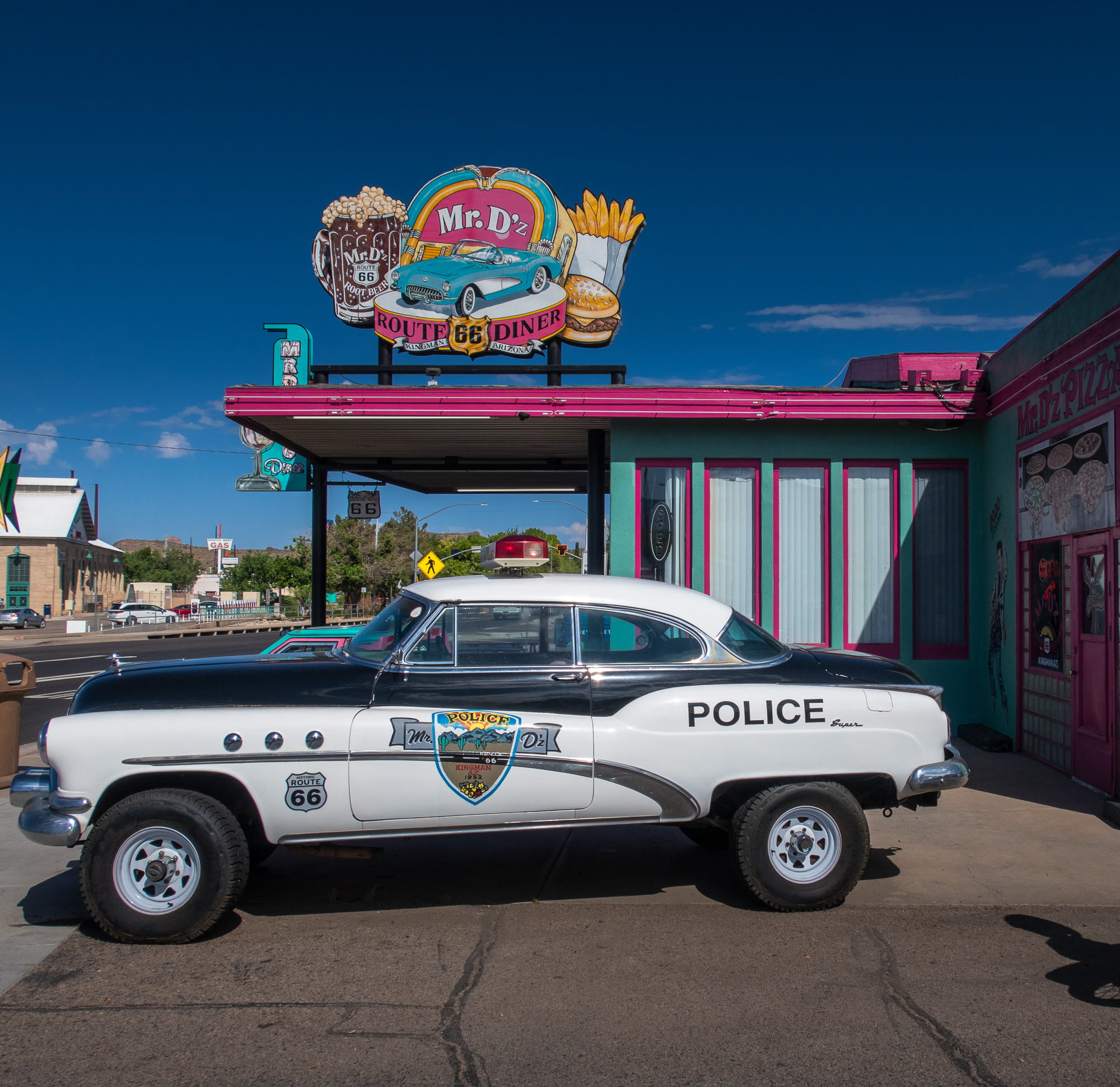 old police car parked next to a burger place 