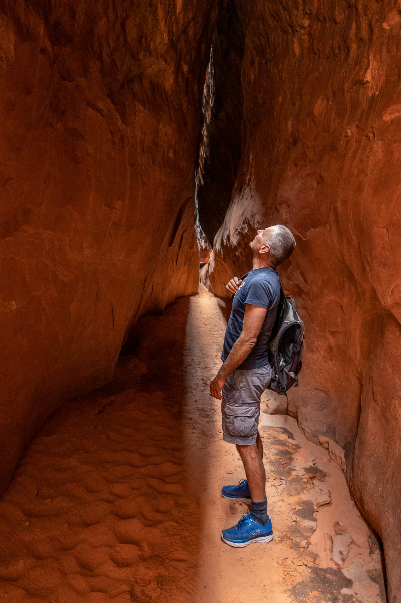 a person looking up steep wals of a slot canyon 