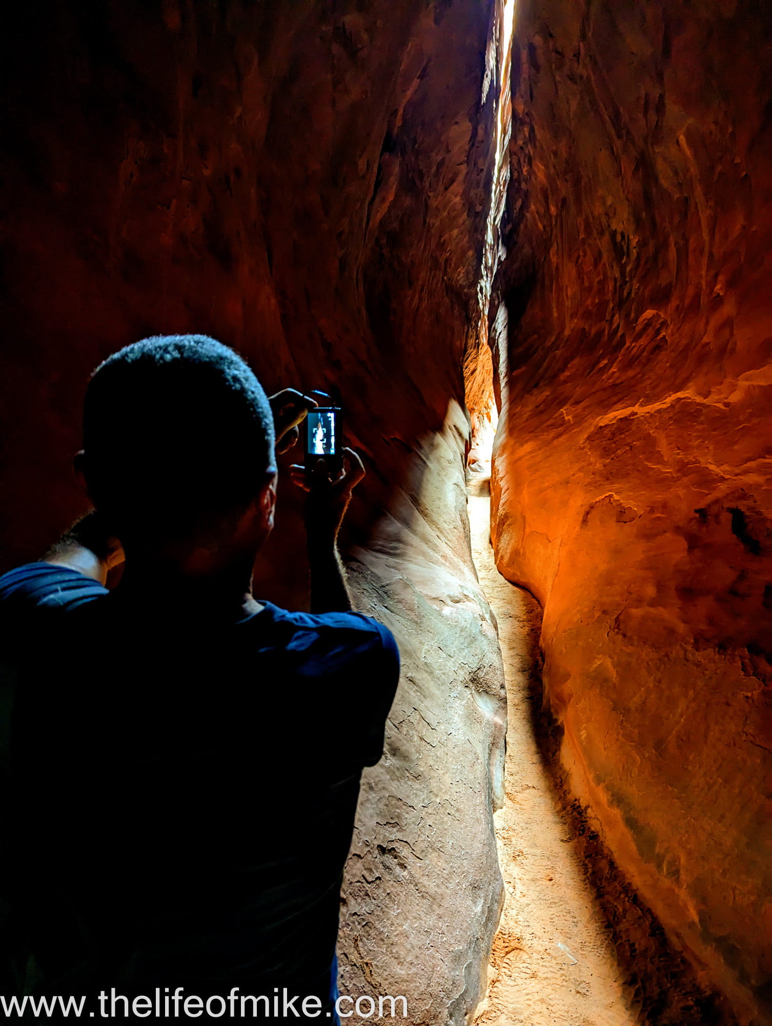 a person taking photos inside a slot canyon 