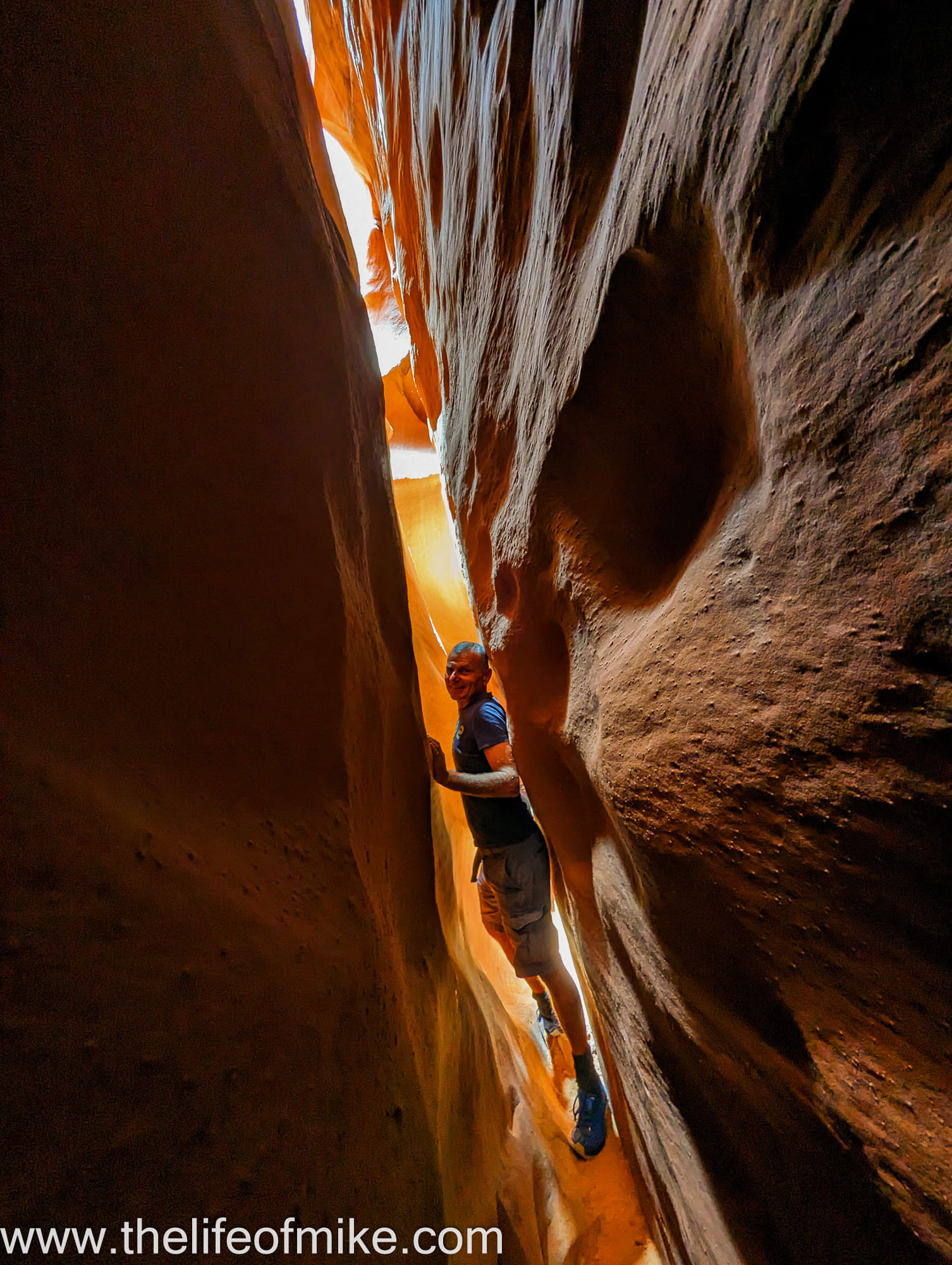 a person squeezing through a narrow canyon walls