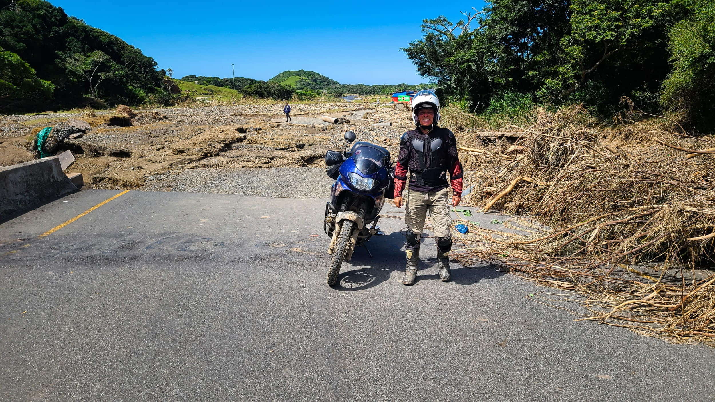 a person and motorcycle next to a washed out bridge