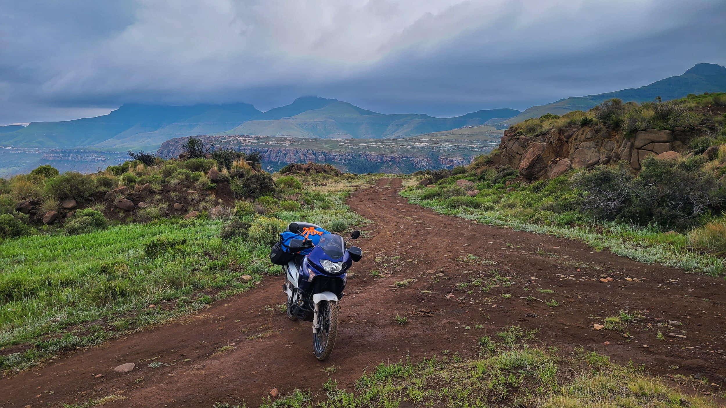 motorcycle on a dirt road with mountains shrouded in clouds behind