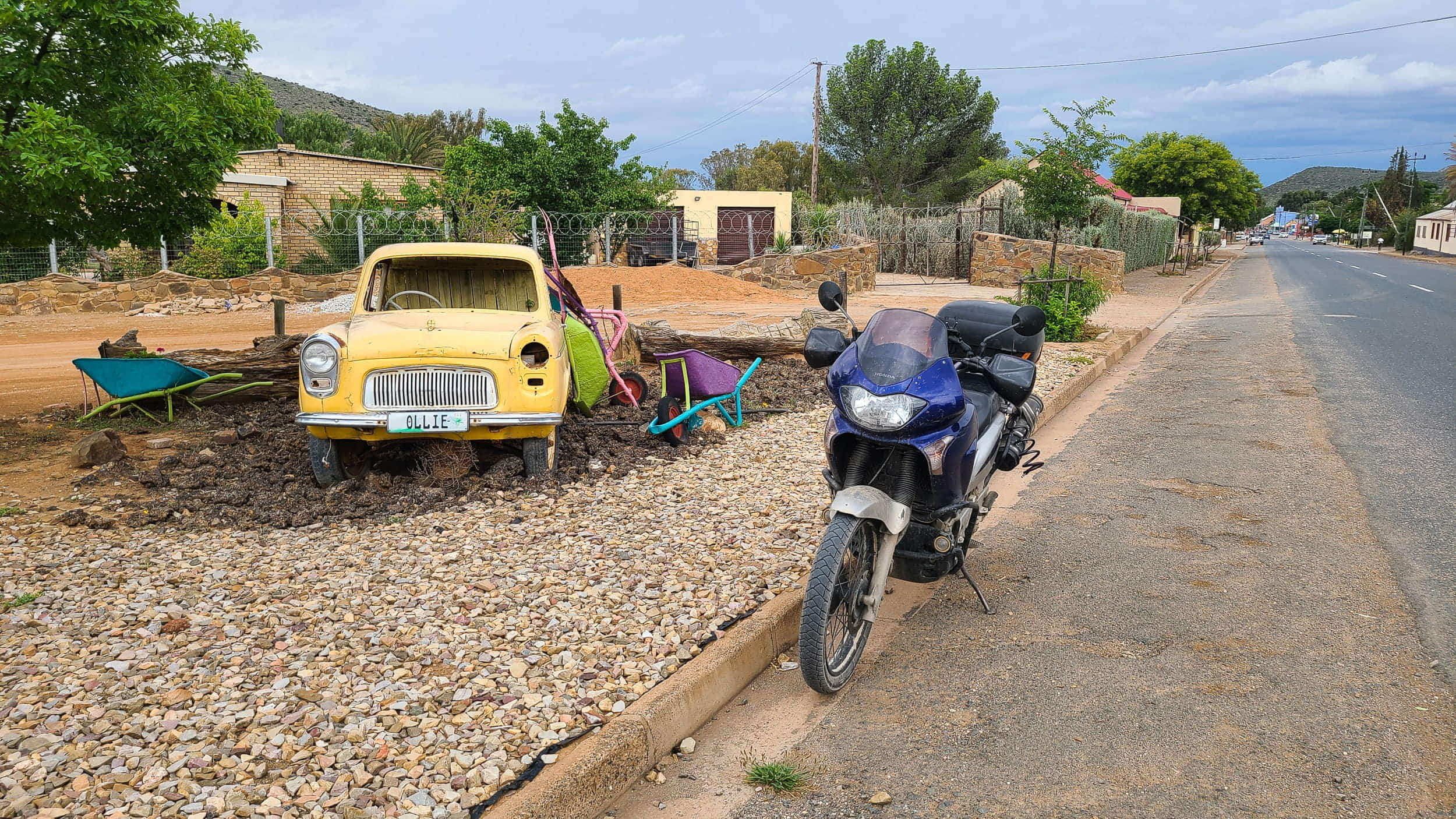 motorcycle parked next to an old car turned into garden