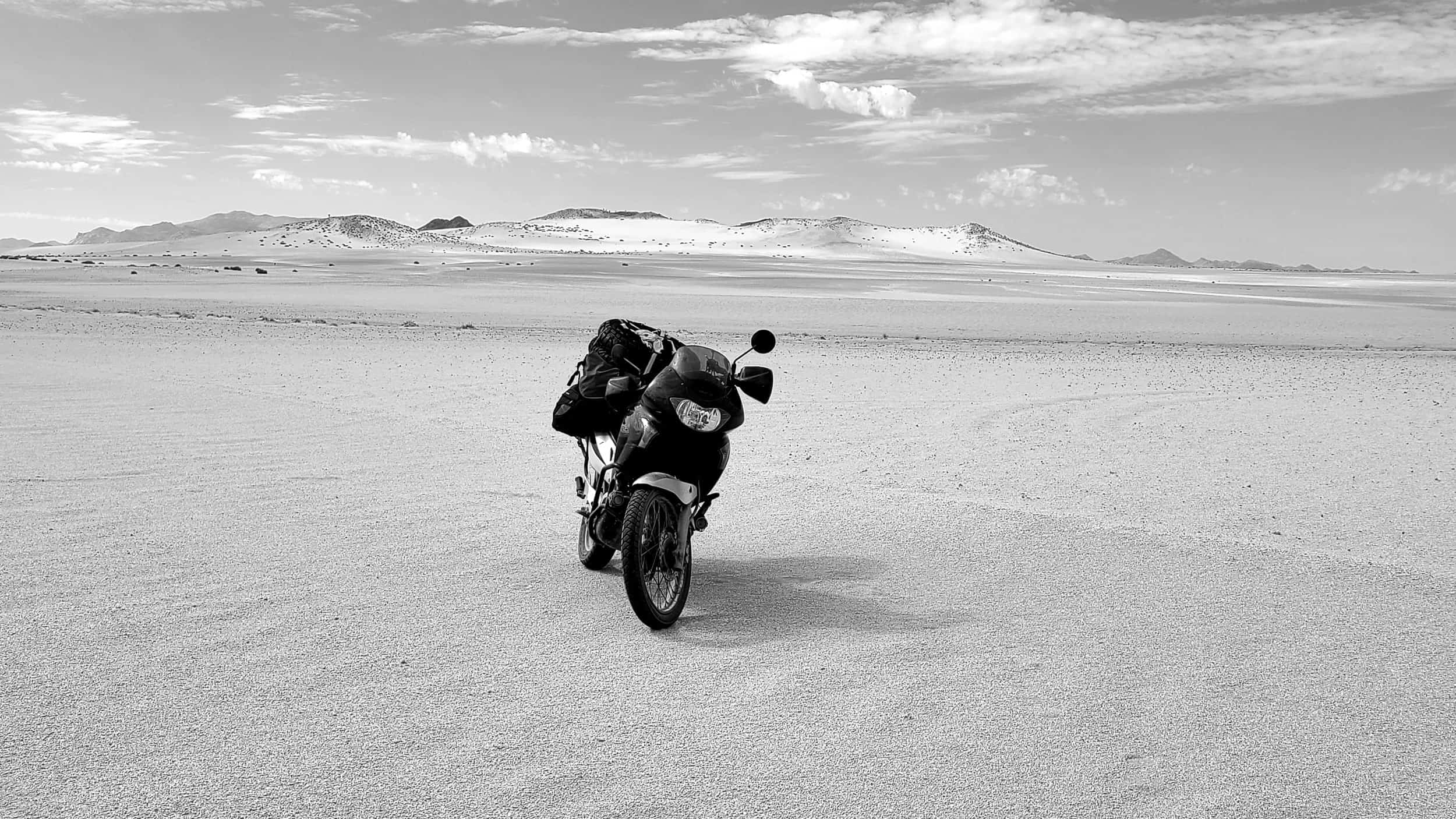 black and white photo of a motorcycle parked in a desertt